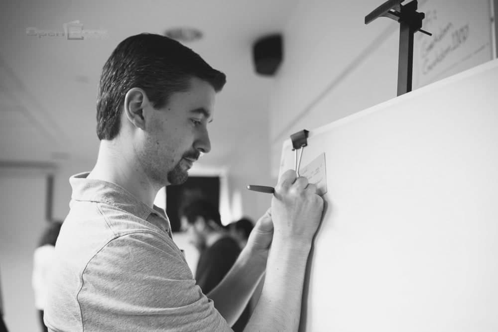 A founder writing on a sticky note at a whiteboard during Geekdom's early days, 2013.